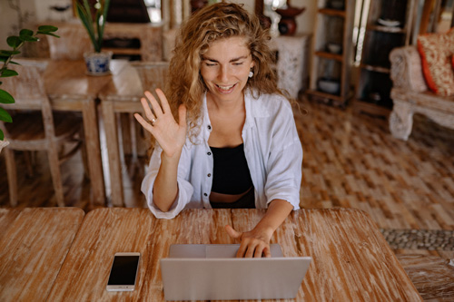 woman waving at laptop computer screen
