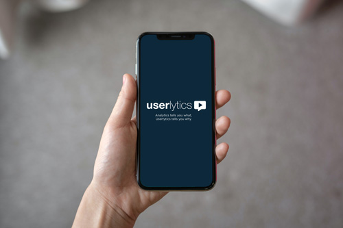 A person holding a phone with Userlytics Logo on the screen.
